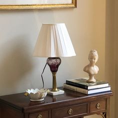 a lamp on top of a wooden table next to a book and a vase with a flower in it