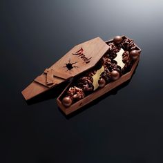 a wooden box filled with lots of chocolates on top of a black tablecloth