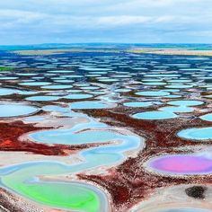 an aerial view of colorful lakes in the middle of nowhere, with blue sky and clouds