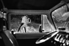 a man and woman dancing in the back seat of a car, taken from behind