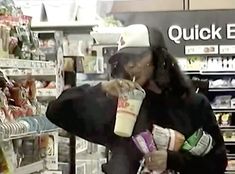 a woman holding a cup in her right hand while standing next to a store shelf