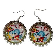 the earrings are decorated with an elephant and circus themed bottle cap, which reads sweet heart