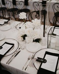 the table is set with black and white place settings, silverware, and flowers