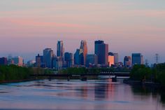 the city skyline is reflected in the still water of the river that runs through it