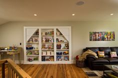 a living room filled with furniture and bookshelves next to a stair case in front of a window