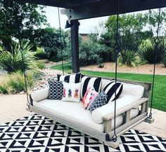 a white couch sitting on top of a black and white rug next to a swing