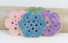 four flower shaped buttons sitting on top of a piece of wood