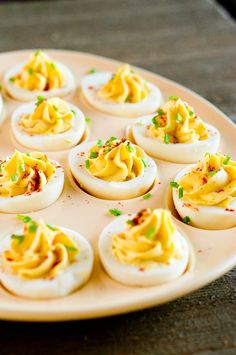 deviled eggs are arranged on a plate with garnishes and seasoning