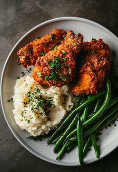 a plate with green beans, mashed potatoes and fried chicken