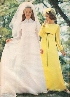 two women in yellow dresses and veils standing next to each other on the grass