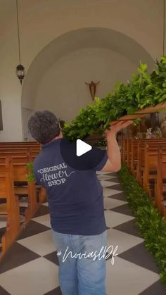 a man is carrying some plants in his hand at the alterp to an empty church