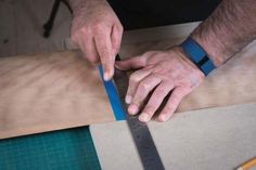 a man is cutting wood with a large blue tape on top of the table next to a pair of scissors