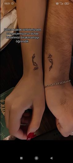 two people with matching tattoos on their arms, one is holding the other's hand