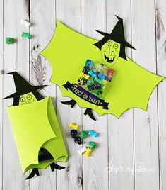 two halloween candy bags sitting on top of a wooden table next to some candies