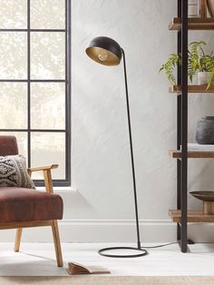 a living room with a chair, lamp and bookshelf