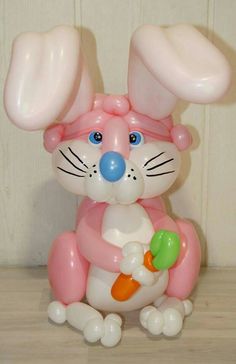 a balloon bunny holding a carrot in it's paws and wearing a pink hat