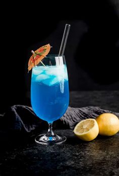 a blue cocktail with lemons and an umbrella