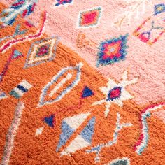 an orange and pink rug with different colored designs