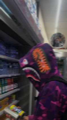 a person wearing a purple and orange hoodie in a grocery store with an animal mask on