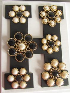 several different types of brooches are displayed on a black and white board with gold accents