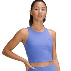 a woman in a blue sports bra top and matching leggings stands with her hands on her hips