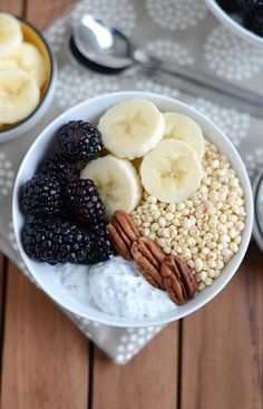 a bowl filled with fruit and nuts next to two bowls of yogurt, banana slices