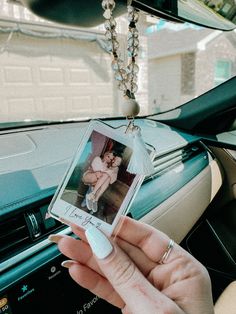 a person holding up a cell phone in their hand with a picture hanging from it