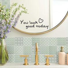 a bathroom sink with two faucets and a vase filled with flowers on it