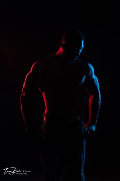 a man standing in the dark with his hands on his hips and arms behind his back