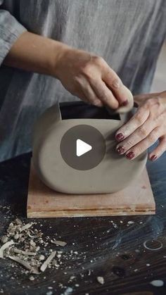 a woman is using a pottery wheel to make a vase on a wooden table with wood shavings around it