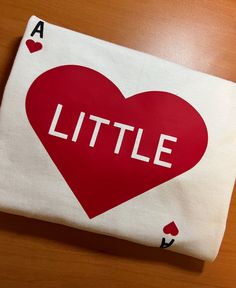 a white bag with a red heart and the word little on it, sitting on top of a wooden table