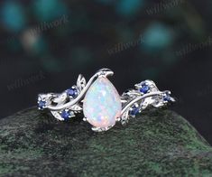 an opal and blue sapphire ring on top of a rock