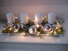 candles and ornaments are arranged on a tray with greenery in the center, surrounded by lights