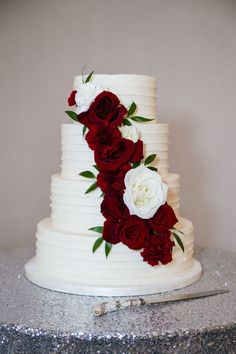 a wedding cake with red and white flowers on it