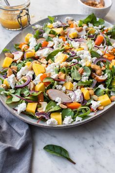 a salad with spinach, carrots, onions and feta cheese on a plate