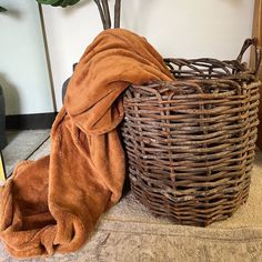 a brown towel sitting next to a wicker basket with a green plant in it