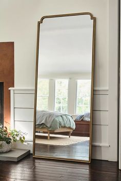 a large mirror sitting on top of a wooden floor next to a fireplace in a living room