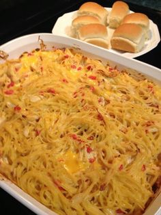 a casserole dish with noodles and cheese on it next to hotdog buns