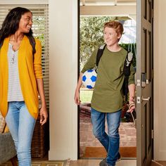 a boy and girl are walking into the house with a soccer ball in their hand