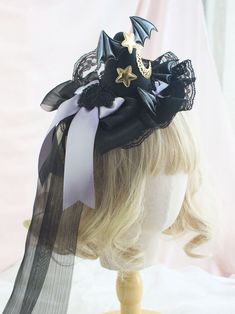 a wig with a black and white headpiece on it's head is shown in front of a pink backdrop