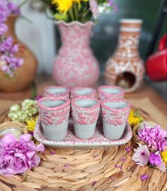 pink and white cups sitting on a tray next to vases with flowers in them