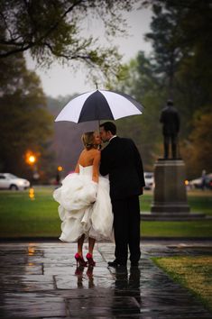 a bride and groom under an umbrella in the rain