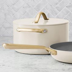 two white pots with gold handles sitting on a marble counter top next to each other