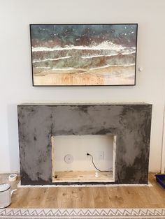 a fireplace is being built in the middle of a room with a painting on the wall