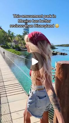 a woman with long blonde hair is standing on a bridge near the water and looking at something