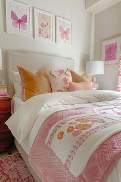 a bed with pink and orange pillows on top of it next to two framed pictures