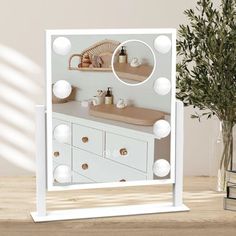 a white vanity mirror sitting on top of a wooden table next to a potted plant