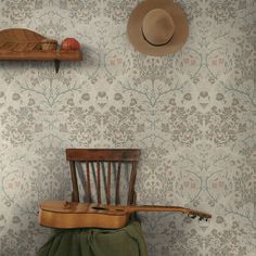 an old wooden chair with a hat on top of it next to a wallpaper