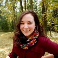 a woman standing in the woods with her hands on her hips and smiling at the camera