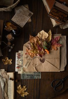 an envelope with autumn leaves on it next to some scissors and other items that are scattered around